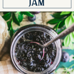 Overhead shot of a spoon in a jar of homemade blueberry jam with text title box at top