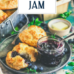 Side shot of blueberry jam and biscuits on a tray with text title overlay