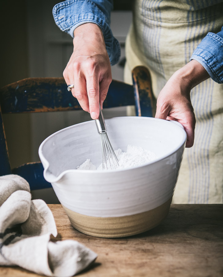 Whisking together dry ingredients in a white bowl.