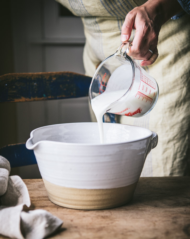 Pouring buttermilk into a white bowl