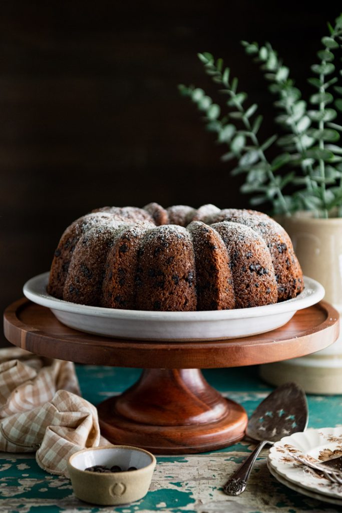 Side shot of a chocolate chip bundt cake on a wooden cake stand
