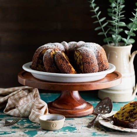 Square featured image of a sliced chocolate chip bundt cake on an antique table