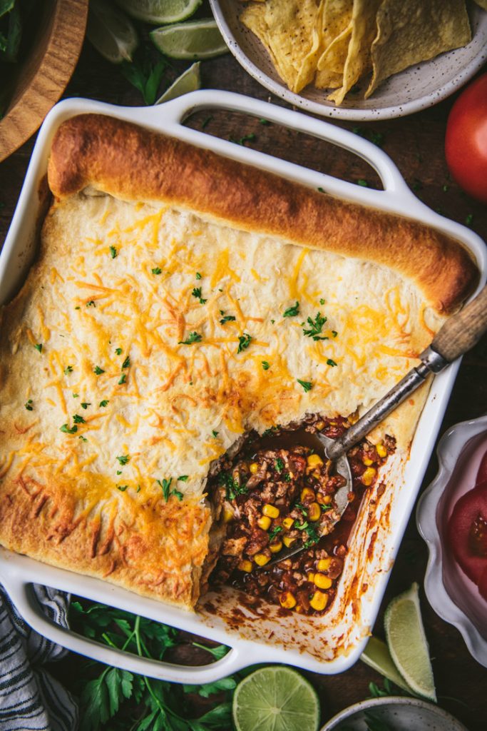 Close overhead shot of a crescent roll taco bake in a white dish
