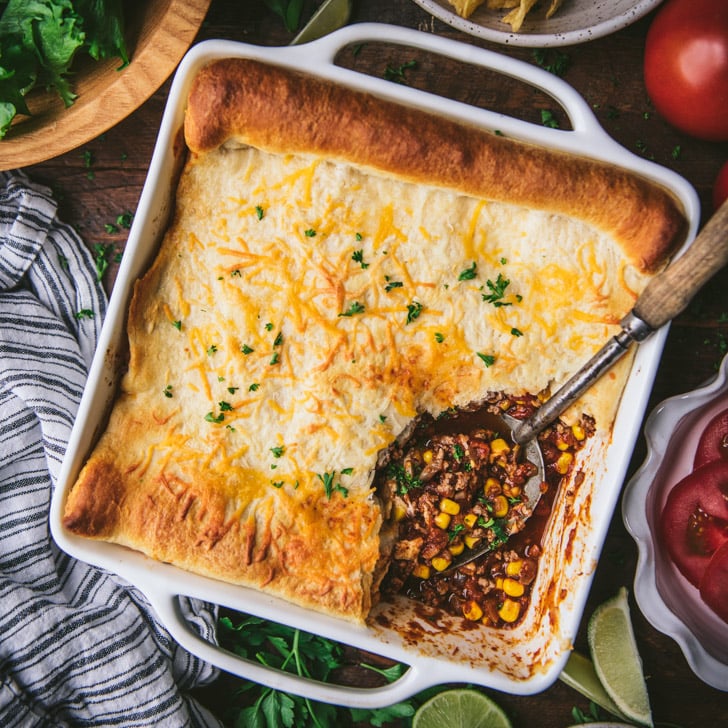 Square overhead shot of crescent roll taco bake with serving spoon