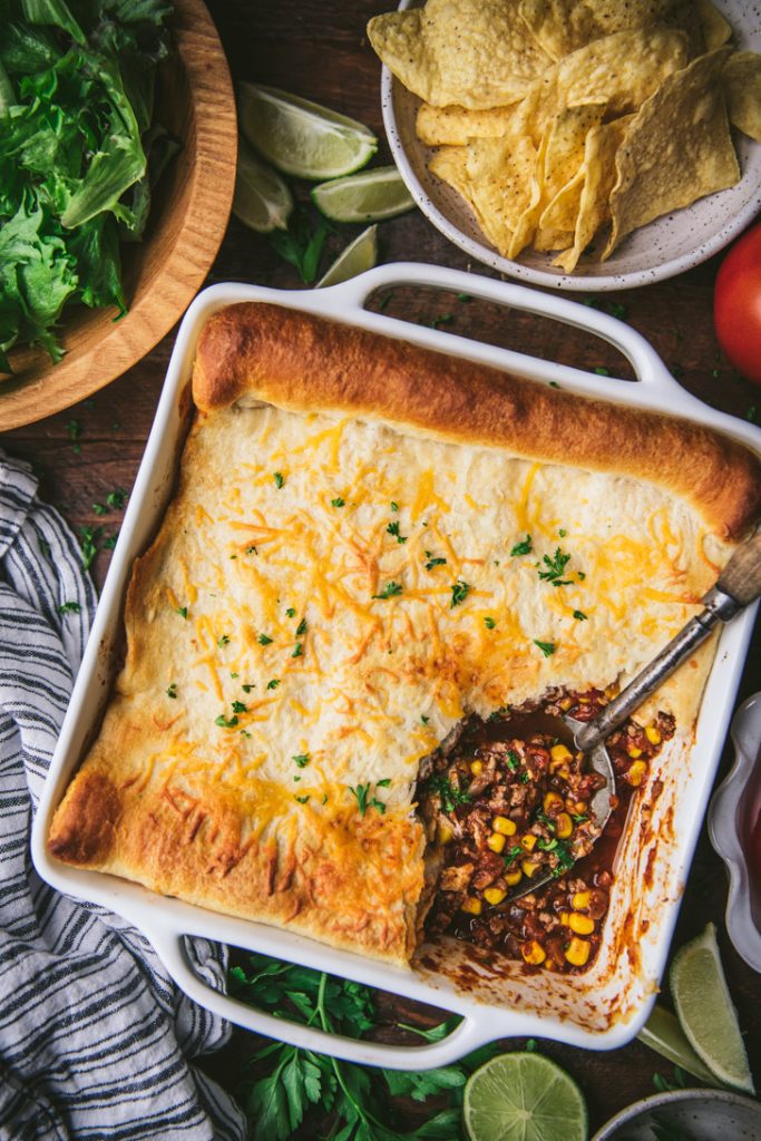 Overhead shot of a crescent roll taco bake with a serving spoon