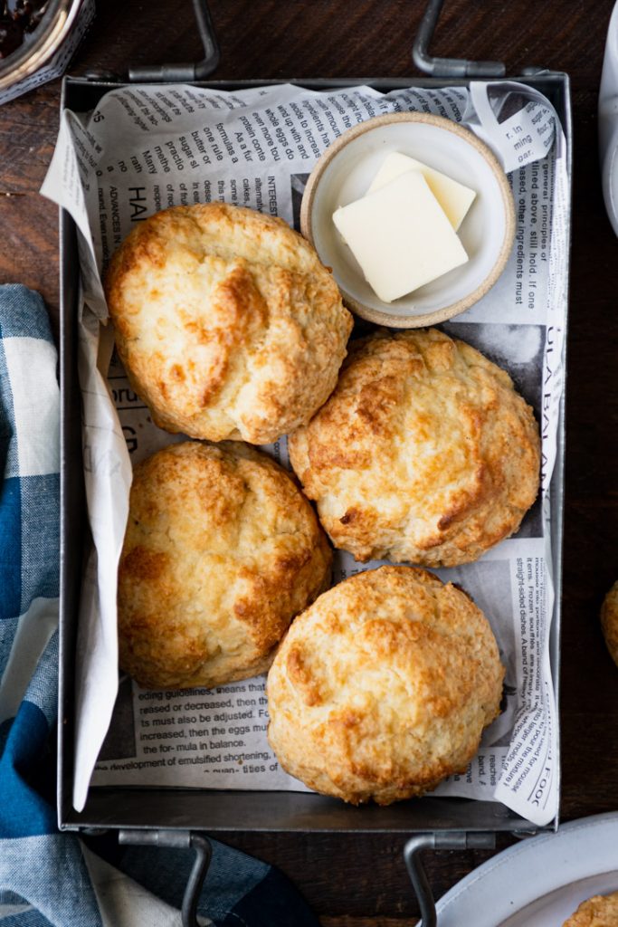 Overhead shot of drop biscuits with butter in a tin