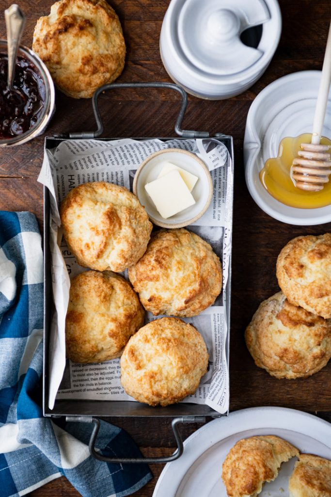 Tin of easy drop biscuits on a wooden table with honey and butter