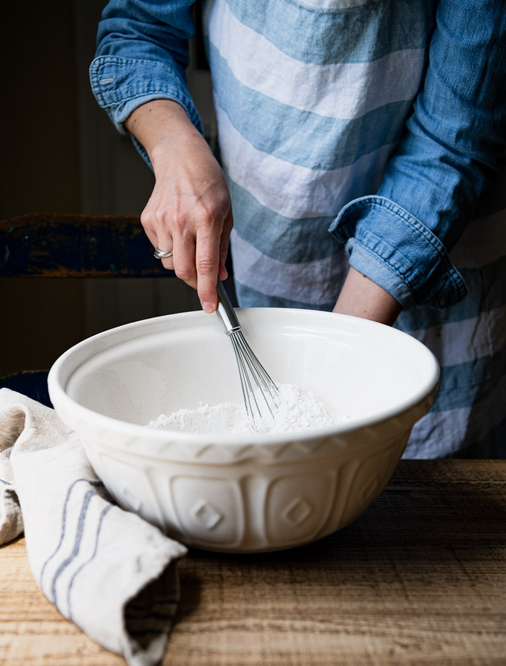 Whisking dry ingredients in a large white bowl