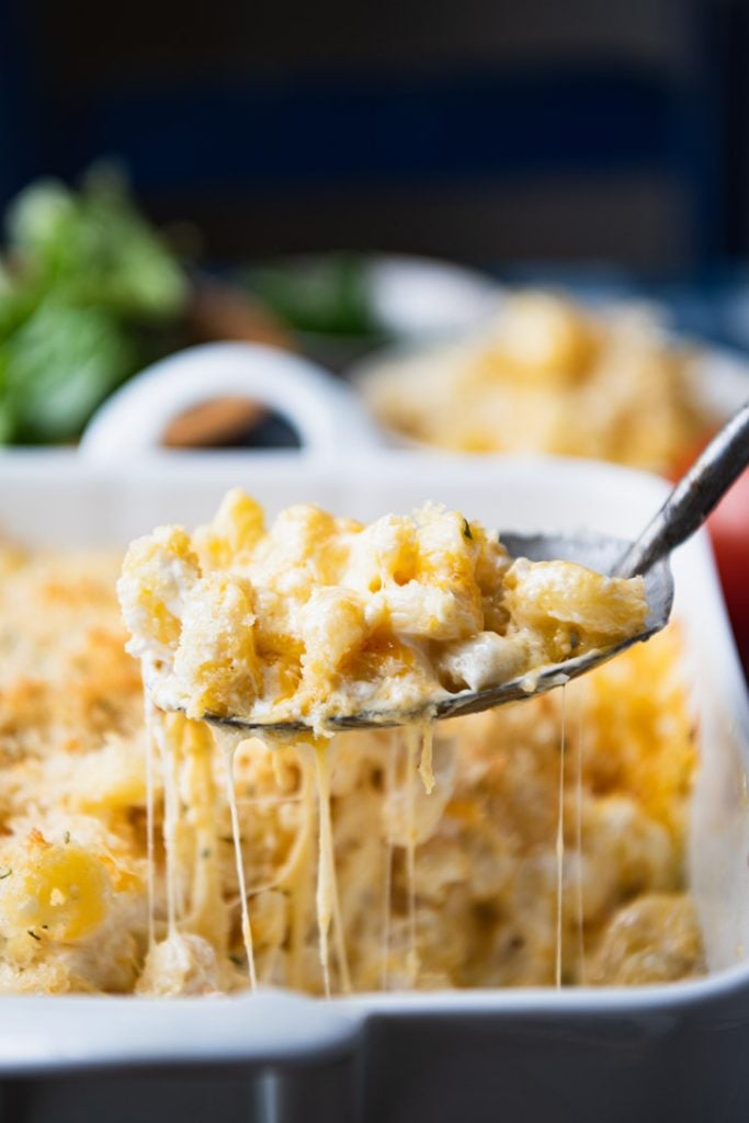 Close up shot of cheese pull on a serving spoon full of mac and cheese