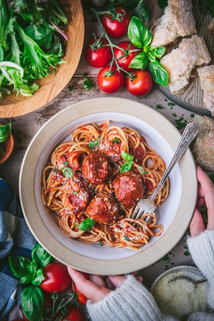 Overhead shot of hands holding a bowl of spaghetti and meatballs