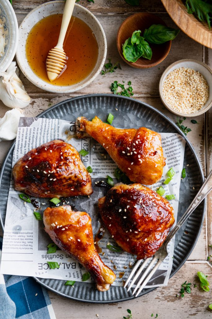 Close overhead shot of baked chicken thighs and drumsticks on a metal platter with honey garlic sauce