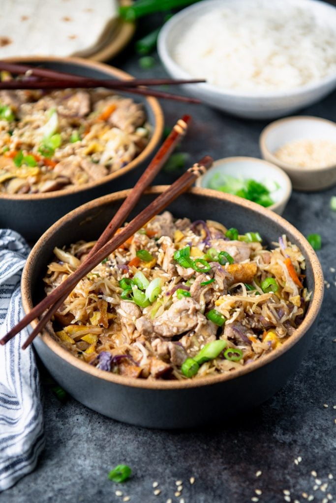 Front shot of two bowls of moo shu pork on a gray surface