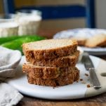 Square featured image of the best zucchini bread recipe stacked on a white serving tray.