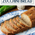 Side shot of sliced loaf of zucchini bread with text title box at top
