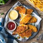Large featured image of a plate of crispy baked chicken tenders with ketchup and honey mustard for dipping