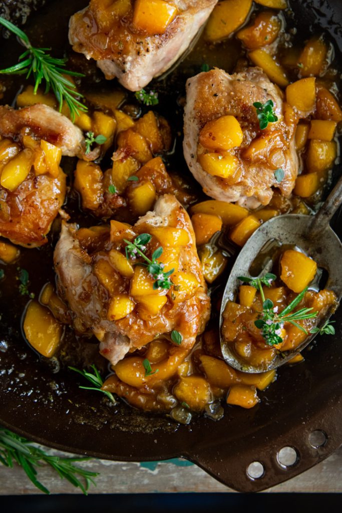 Close overhead shot of peach chicken thighs in a skillet