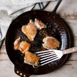 Pan frying chicken thighs in a cast iron skillet