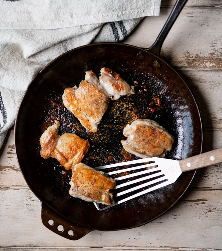 Pan frying chicken thighs in a cast iron skillet