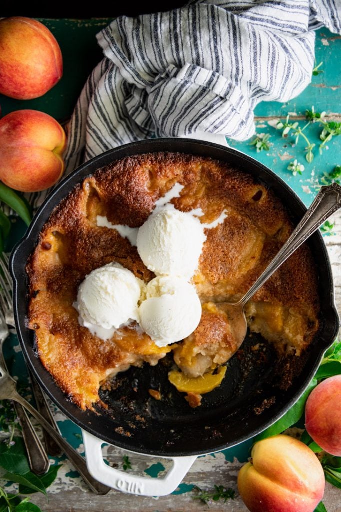 Overhead image of a skillet of the best peach cobbler recipe with ice cream on top