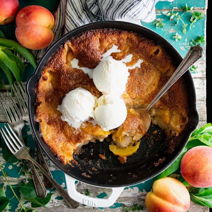 Easy peach cobbler recipe in a cast iron skillet with ice cream on top
