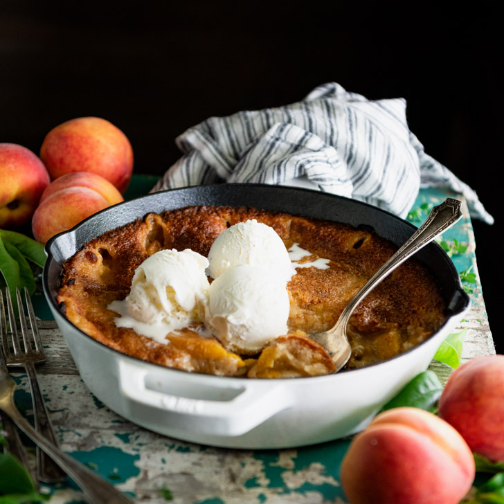 Square side shot of a peach cobbler baked in a cast iron skillet