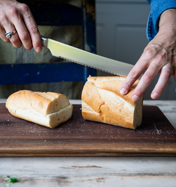 Slicing french bread on a cutting board