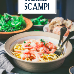 Side shot of a bowl of shrimp scampi on a dinner table with text title overlay