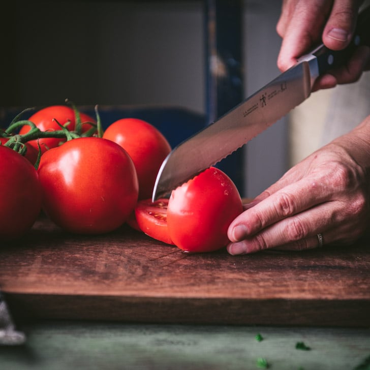 Slicing a tomato on a wooden cutting board