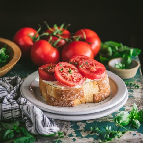 Square featured image of a southern tomato sandwich on a white plate with fresh basil