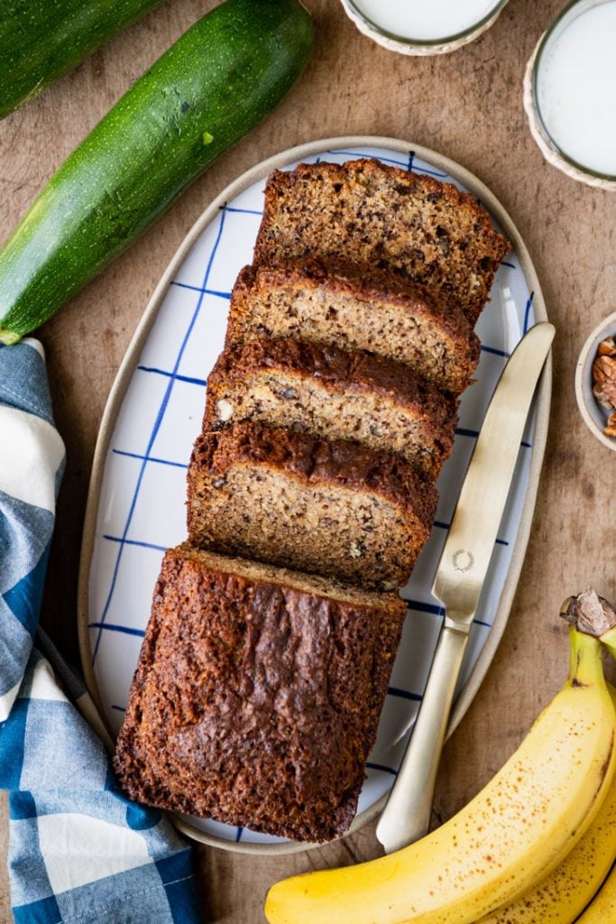 Overhead shot of a sliced loaf of zucchini banana bread on a tray