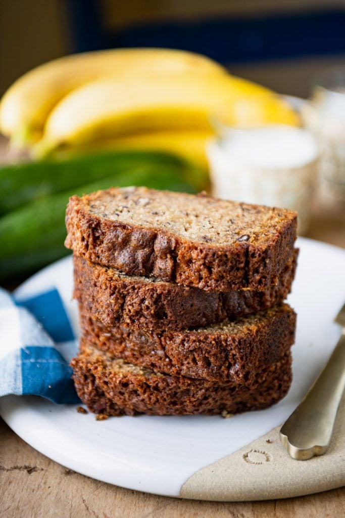 Four stacked slices of the best zucchini banana bread recipe on a white platter