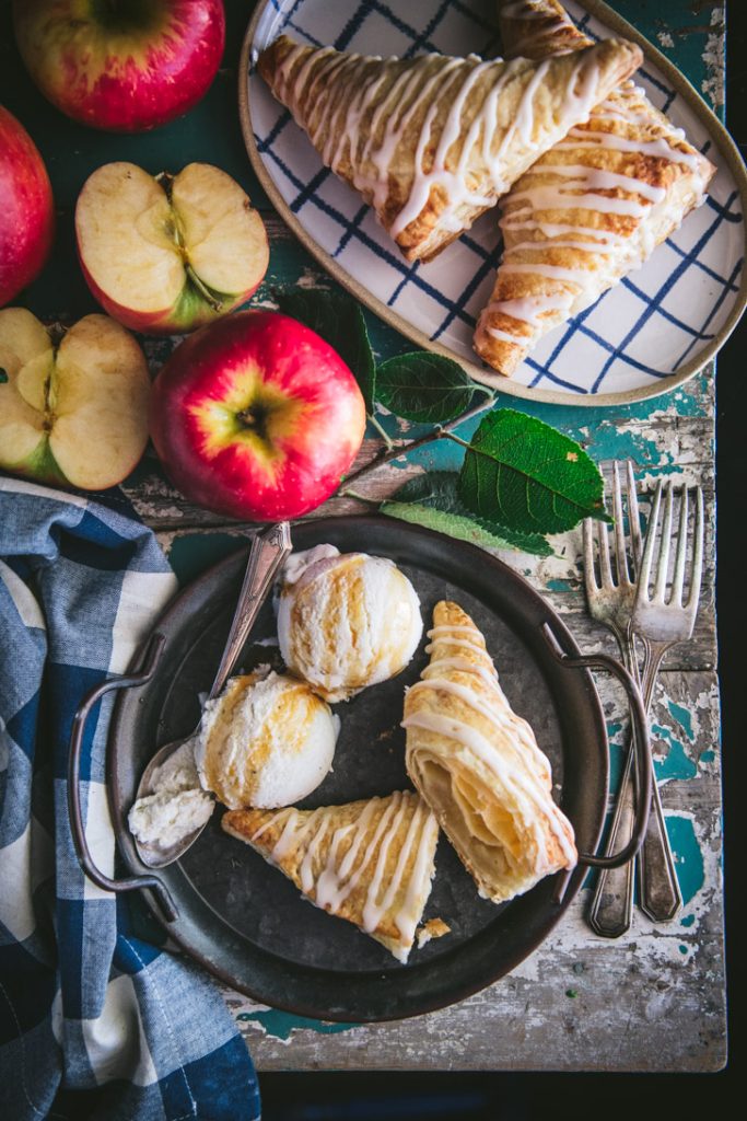 Apple turnover on a plate and cut in half with ice cream on the side