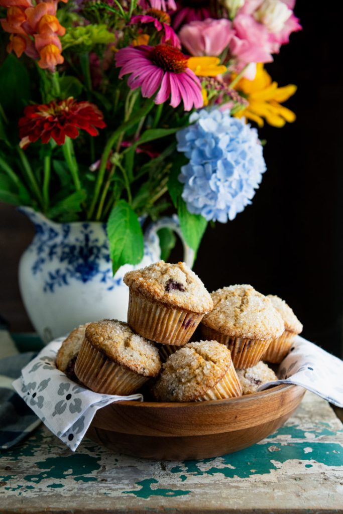 Basket of blackberry muffins in front of flowers