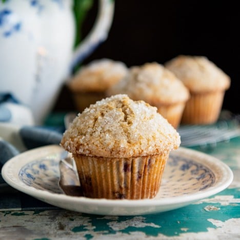 Close up side shot of a homemade blackberry muffin recipe served on a blue and white plate