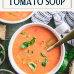 Overhead shot of a spoon in a bowl of roasted tomato soup with text title box at top