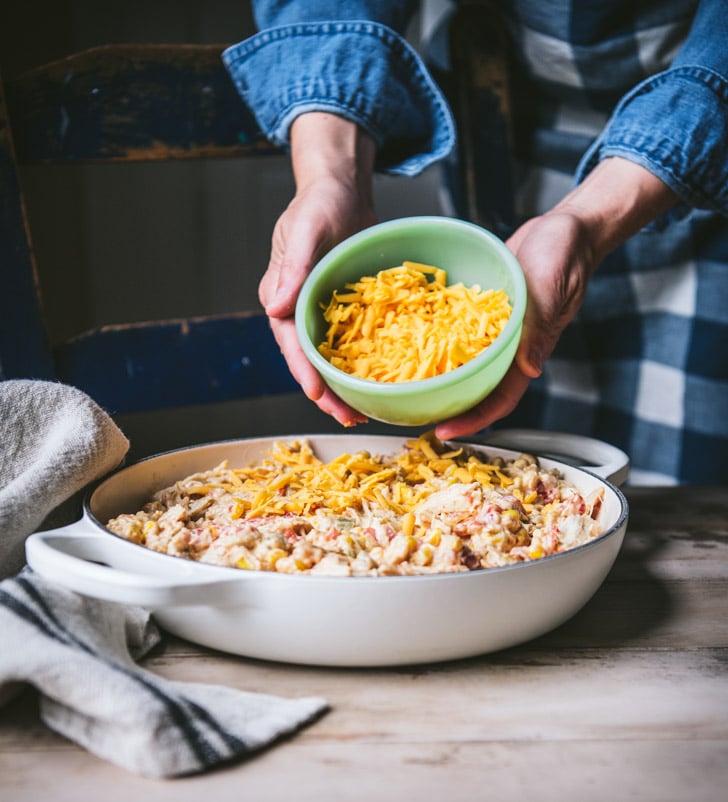 Adding shredded cheese to the top of a casserole