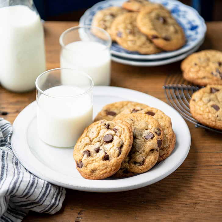 Square side shot of a plate of easy chocolate chip cookies on a table with milk