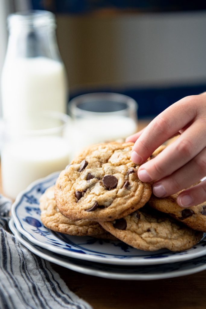 Kid's hand picking up a chocolate chip cookie