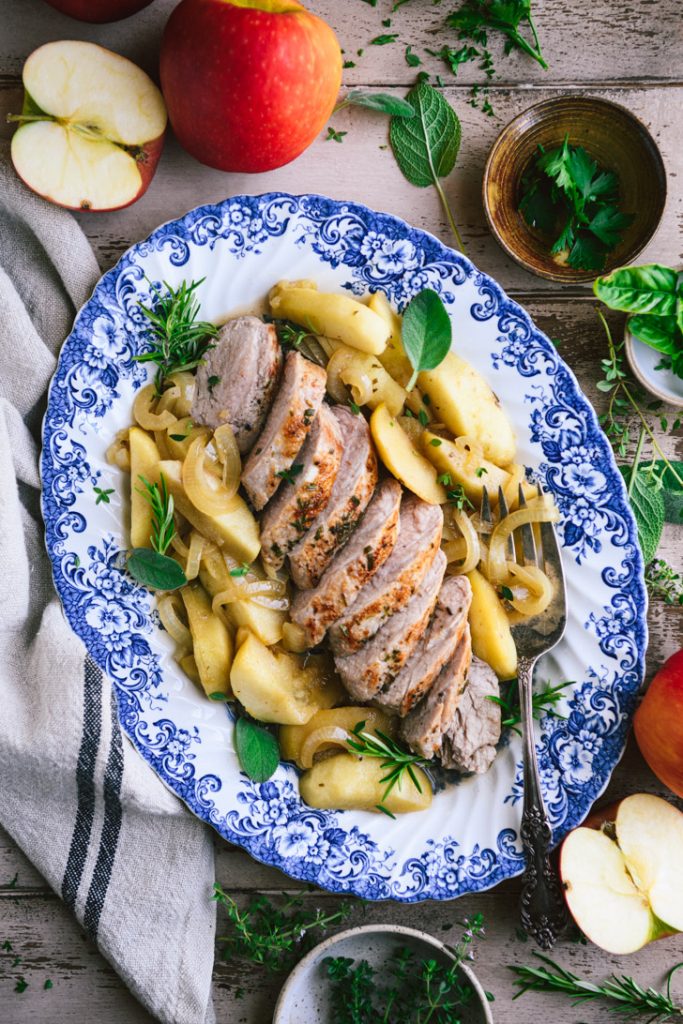 Overhead shot of pork tenderloin with apples on a blue and white tray