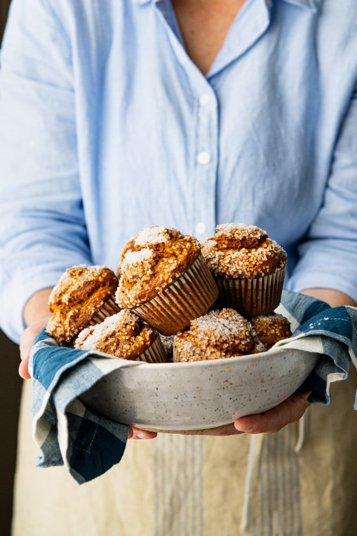 A woman holds a bowl of easy homemade pumpkin muffins in her hands.