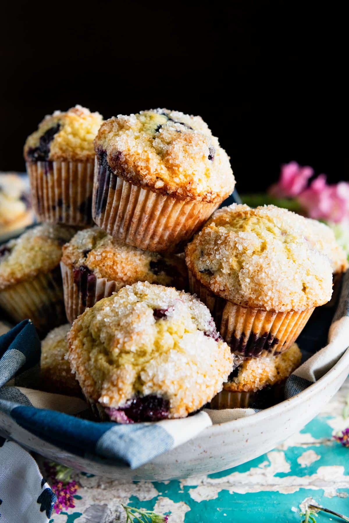 Bowl of bakery style blueberry muffins on a table.