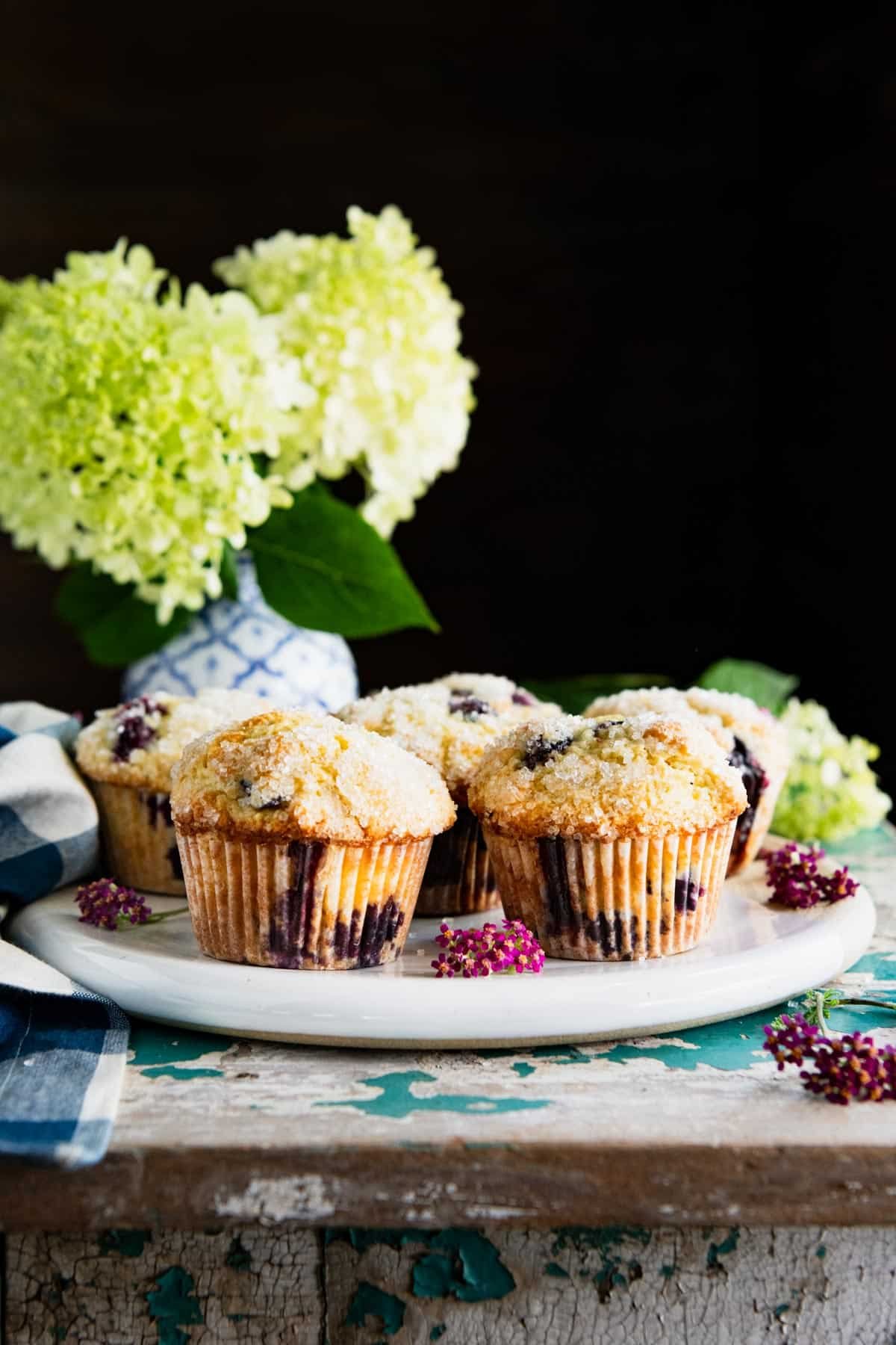 Plate of sour cream blueberry muffins on a rustic turquoise wooden chest.