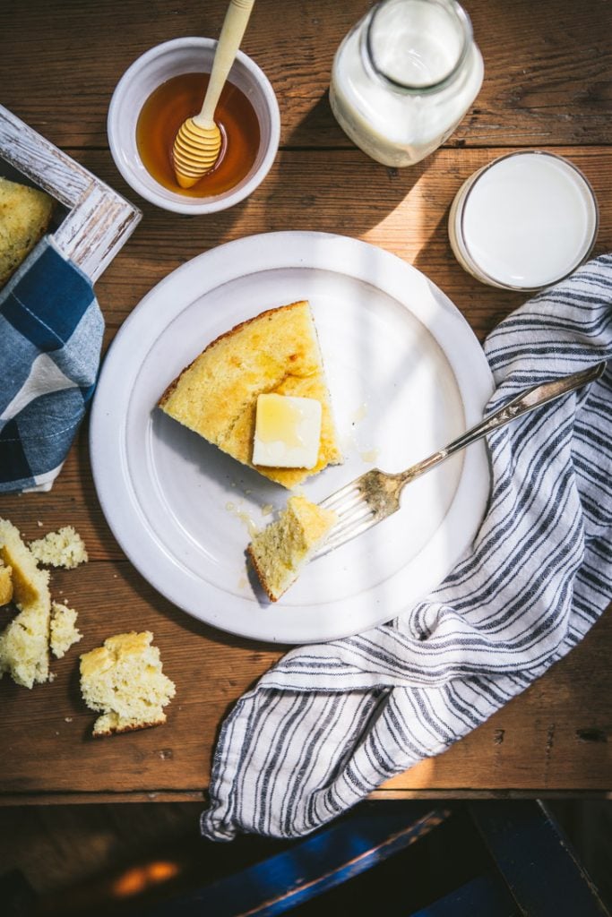 Overhead shot of a slice of southern cornbread recipe on a white plate with a fork