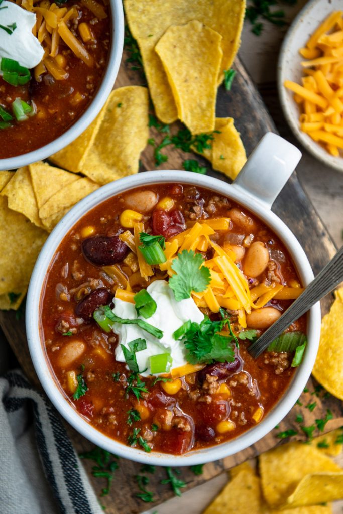 Overhead image of taco soup in a white bowl with tortilla chips on the side