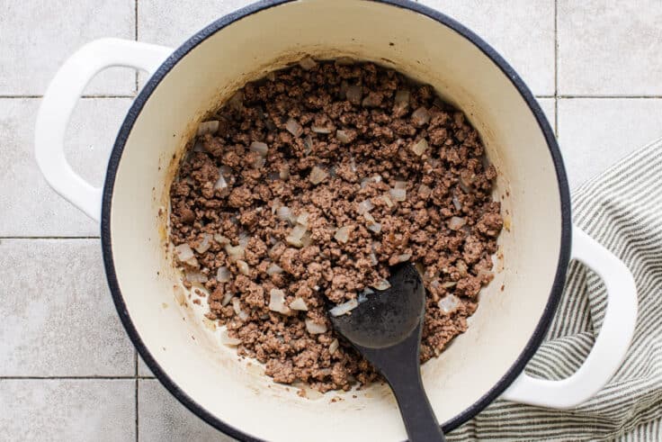 Browning ground beef in a Dutch oven for a chili mac recipe.