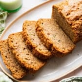 Square side shot of a loaf of sliced zucchini bread on a white serving tray.