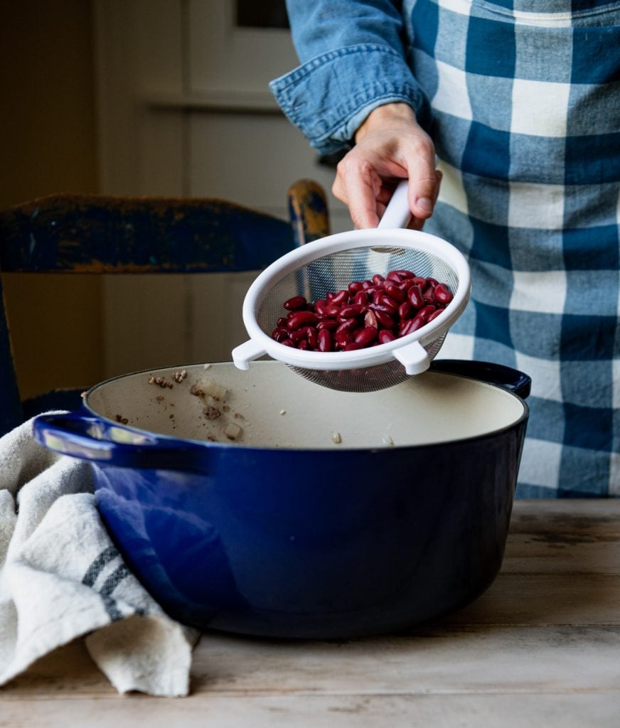 Adding kidney beans to a blue Dutch oven