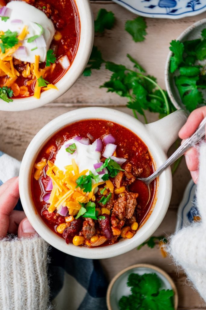 Overhead shot of hands eating a bowl of chili