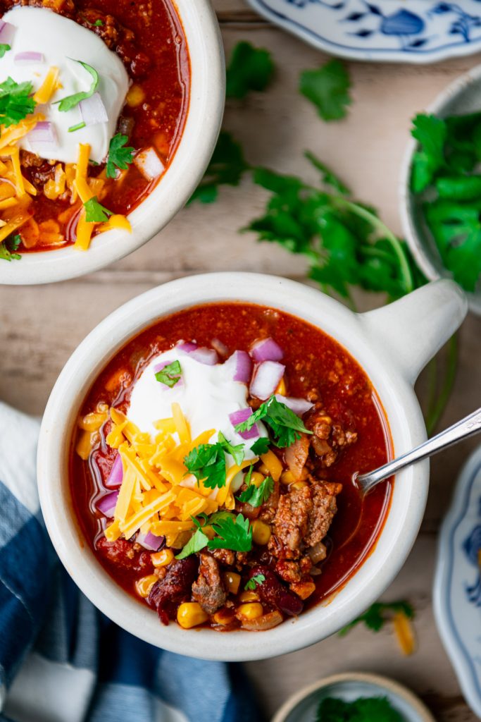 Overhead shot of a bowl of beef and beer chili on a wooden table