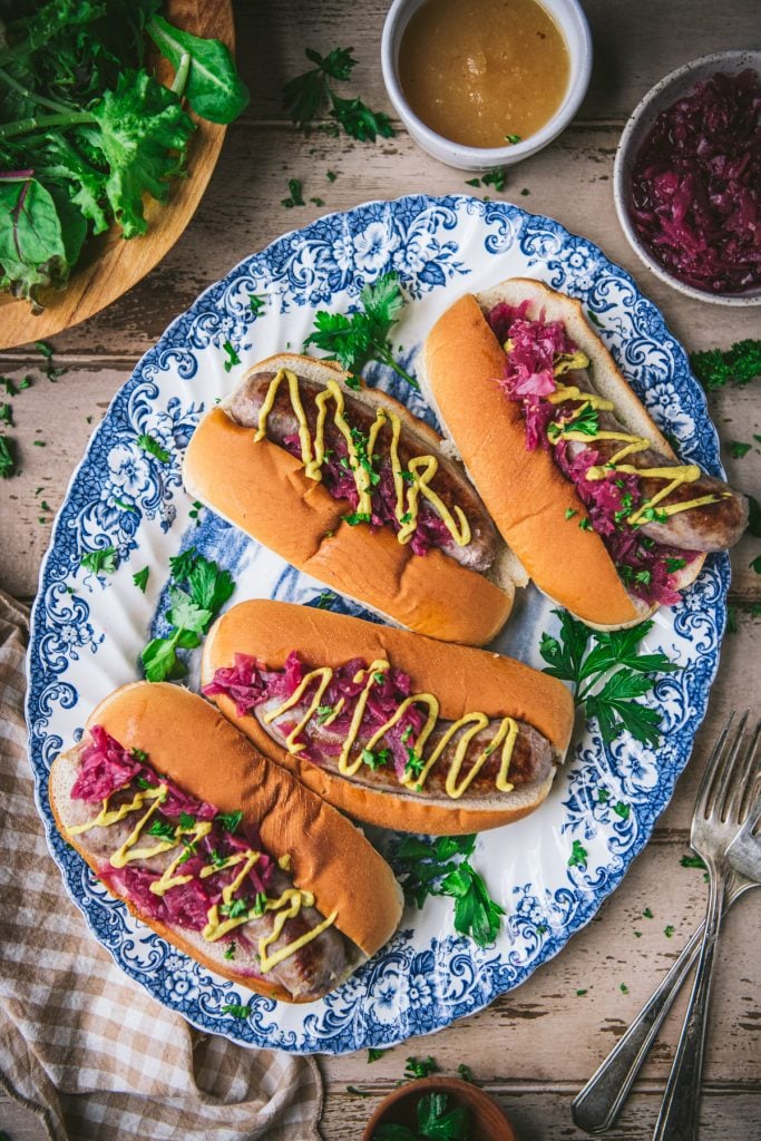 Blue and white tray of beer brats on sandwiches with cabbage and mustard